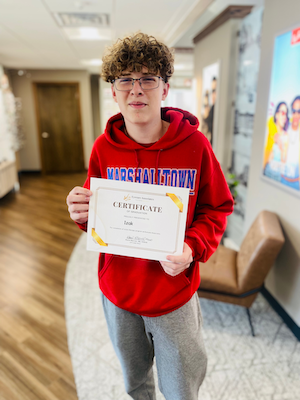 Izak smiling while holding a certificate